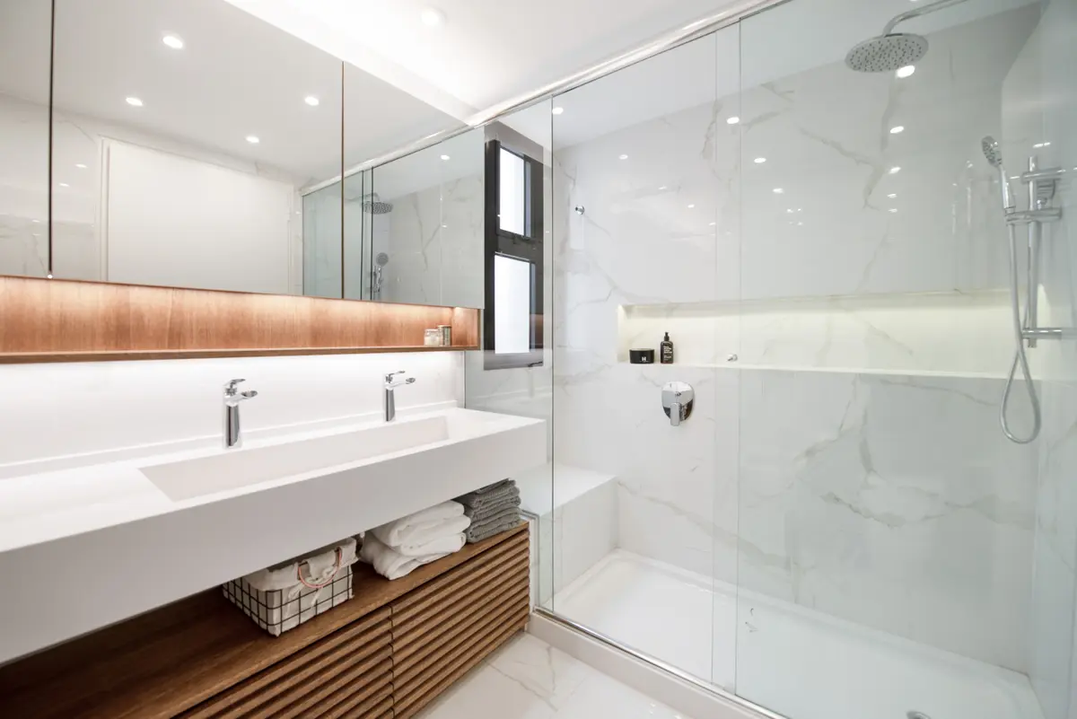 Baño moderno con doble lavabo, paredes de mármol y almacenamiento de madera — proyecto Depto Amenabar, por Ayelen Mayer Arquitectura, en Buenos Aires